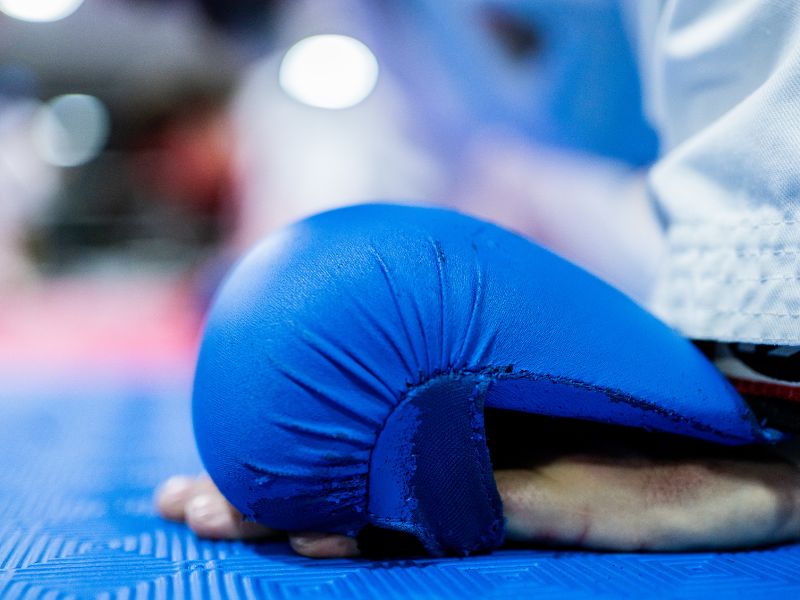 Detailaufnahme eines blauen Karate-Handschutzes auf der Trainingsmatte, symbolisierend für Schutz und Sicherheit während des Karate Kumite Trainings.