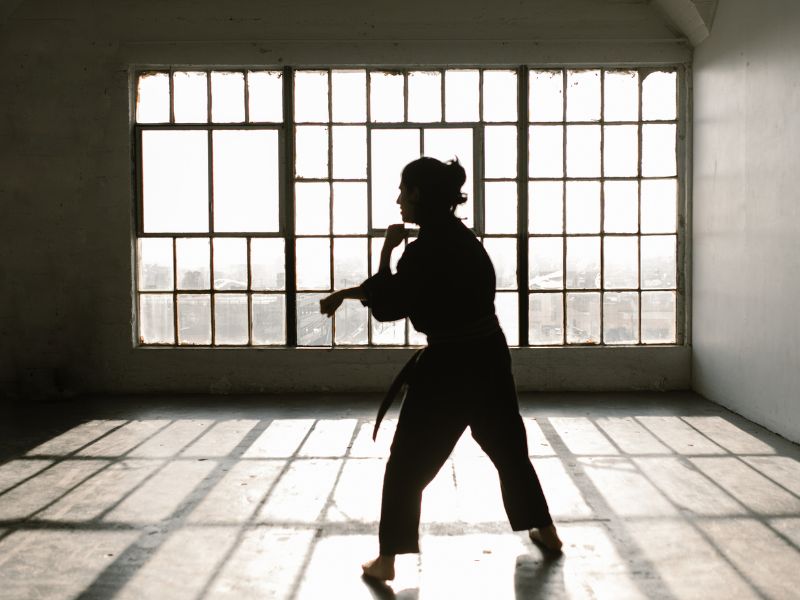 Silhouette eines Karateka, der in einem lichtdurchfluteten Raum trainiert, symbolisierend für Ruhe, Fokus und die meditative Seite des Karate Kumite.