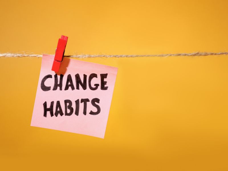 Zettel mit der Aufschrift 'Change Habits' an einer Wäscheleine auf gelbem Hintergrund