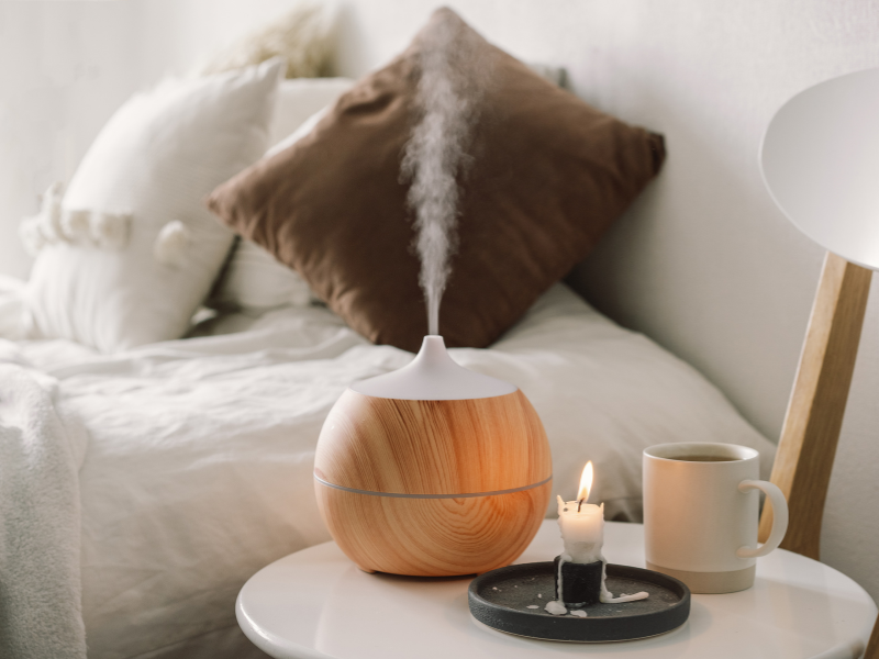 Aroma Diffuser verströmt Duft neben Kerze, Tasse Tee und Kissen – perfekte Hygge Idee Herbst